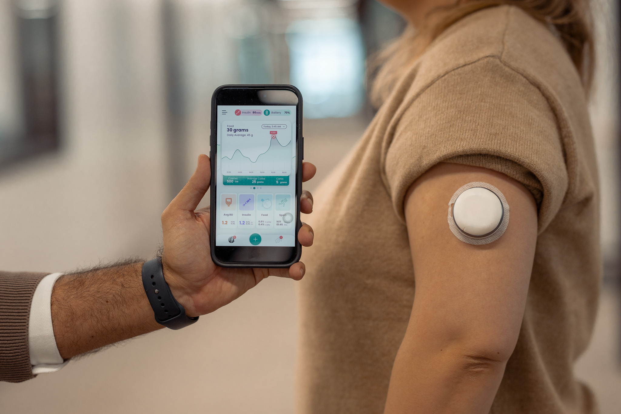 Person wearing the Pocket Clinic 7-Day Smart Injector on the upper arm, with its readout shown on a smartphone